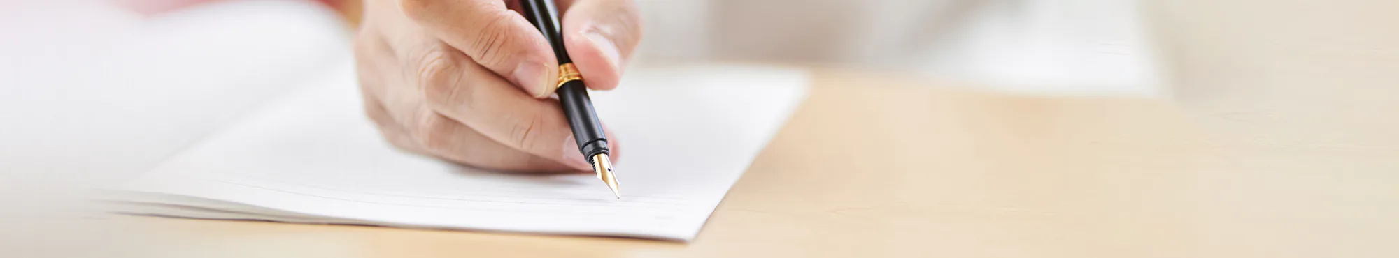 Eine Hand schreibt mit Füllhalter in ein Dokument. Es ist wichtig, Vorsorgedokumente für den Ernstfall ausgefüllt zu haben